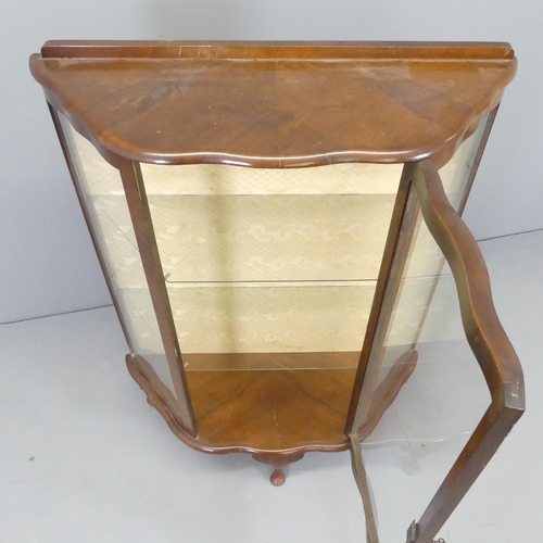 2587 - A 1930s walnut glazed display cabinet of serpentine form, with two fixed shelves and raised on cabri... 