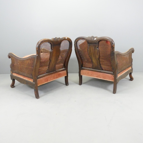 2592 - A pair of Georgian walnut bergere arm chairs with cane panels. A/F.