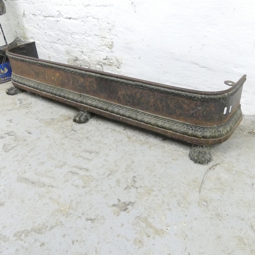 2604 - A cast iron fire fender with brass lion paw feet. 130x26x32cm.