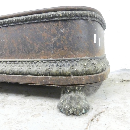 2604 - A cast iron fire fender with brass lion paw feet. 130x26x32cm.