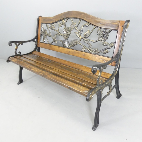 2606 - A pine slatted garden bench with cast iron ends and painted metal floral-design back panel. 130x89x6... 