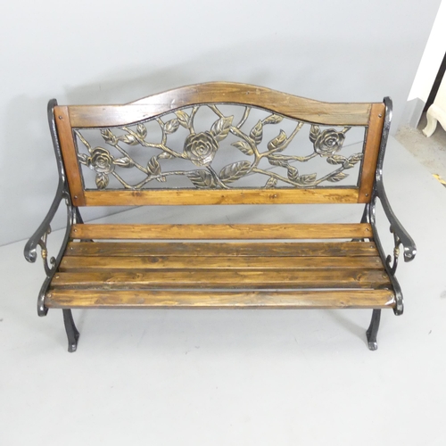 2606 - A pine slatted garden bench with cast iron ends and painted metal floral-design back panel. 130x89x6... 