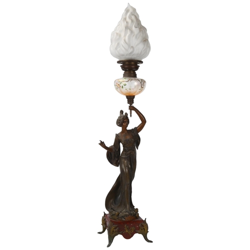 137 - An Art Nouveau oil lamp, supported by a bronze patinated spelter figure of a woman, lustre glass ves... 