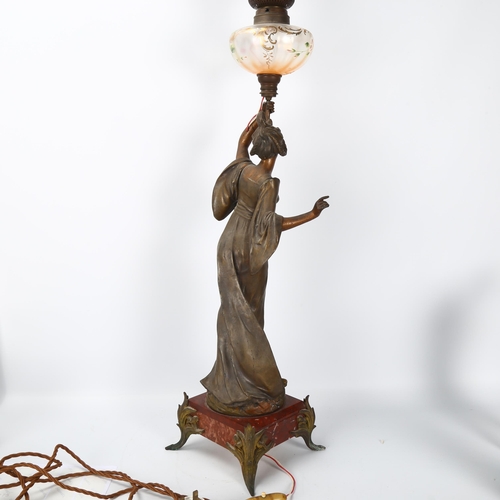 137 - An Art Nouveau oil lamp, supported by a bronze patinated spelter figure of a woman, lustre glass ves... 