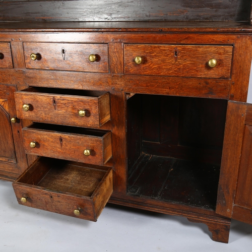 48 - A George III Welsh oak dresser, with plate rack and fielded panelled doors with brass knob handles, ... 