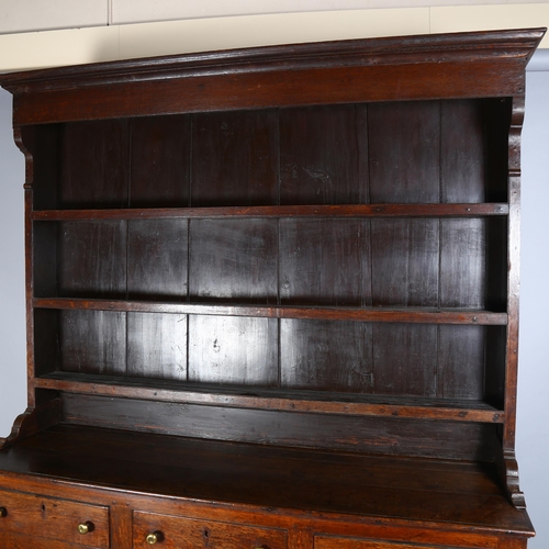 48 - A George III Welsh oak dresser, with plate rack and fielded panelled doors with brass knob handles, ... 