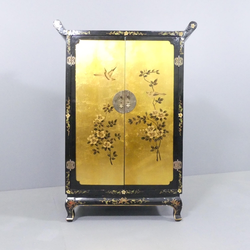 2006 - A contemporary Oriental black lacquered two door cabinet, with gilt painted and gold leaf decoration... 