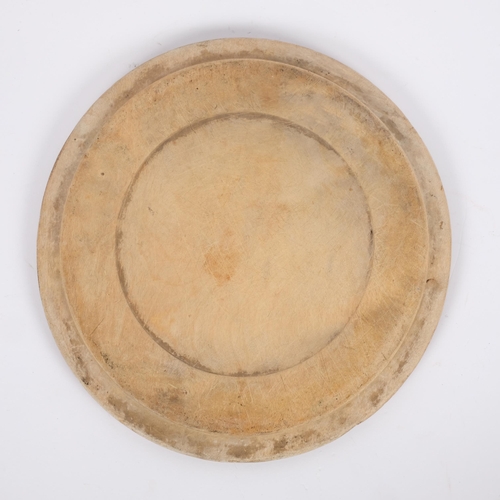 10 - A 20th century bread board with carved decoration, diameter 29cm