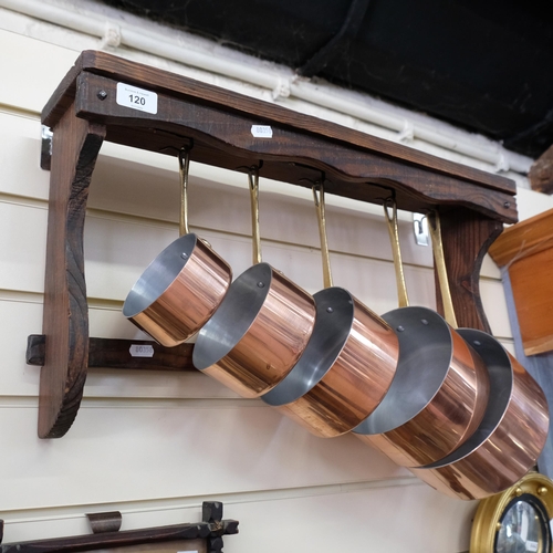 120 - A graduated set of 5 copper bound and brass-handled pans, complete with an oak hanging rack