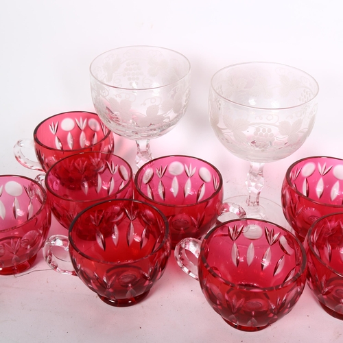 353 - A collection of cranberry overlay cups, and a pair of engraved glasses with cut stems