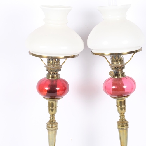 53 - A pair of Victorian brass oil lamps of tapered form, with milk glass shades and cranberry fonts, H52... 