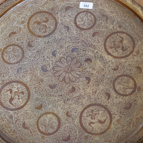 582 - A large brass Indian table-top tray, diameter 57cm, decorated with floral decoration including vario... 