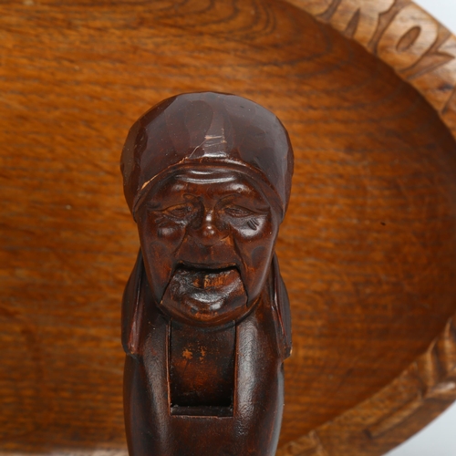 910 - A Black Forest carved wood nutcracker in the form of a woman's head, and a German carved oak bread b... 