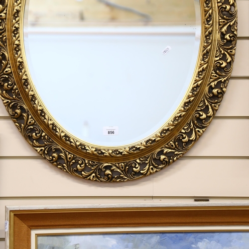 856 - A large wooden oval wall-hanging bevel-edge mirror, in ornate giltwood frame, 76cm x 63cm