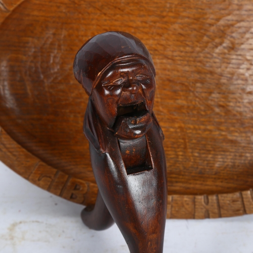 910 - A Black Forest carved wood nutcracker in the form of a woman's head, and a German carved oak bread b... 