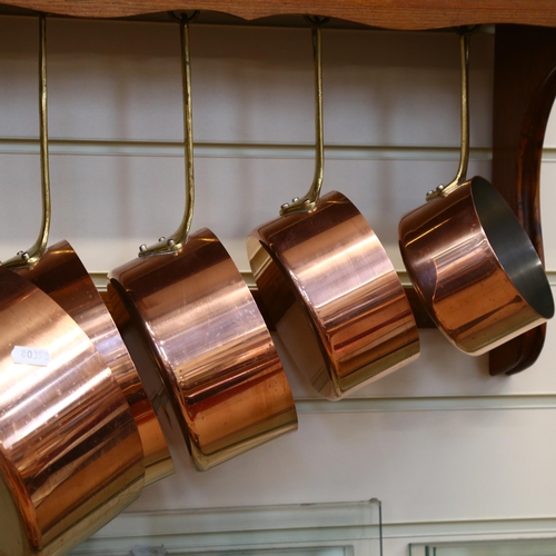 1045 - A graduated set of 5 French copper steel and brass-handled pans, and stained pine hanging rack, W60c... 