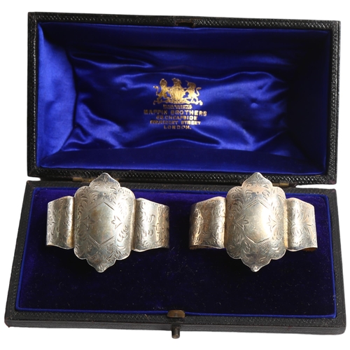 1298 - A pair of Edward VII engraved silver napkin rings, standing on ball feet, in fitted box, retailed by... 