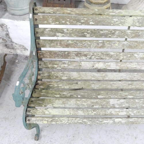 2658 - A weathered teak slatted garden bench with cast iron ends. 130x83x65cm.