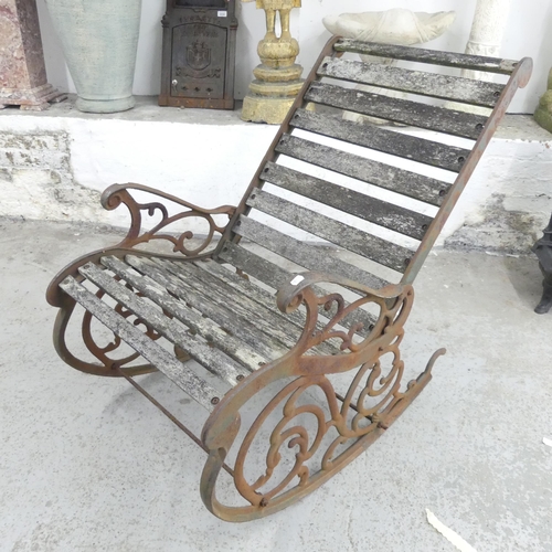 2657 - A weathered teak-slatted garden rocking chair with cast iron frame. Overall 63x90x97cm.