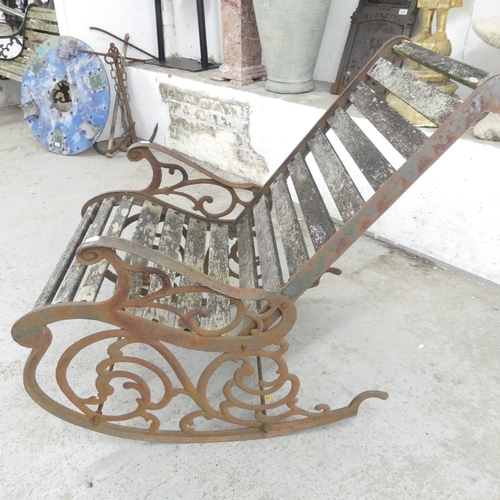 2657 - A weathered teak-slatted garden rocking chair with cast iron frame. Overall 63x90x97cm.