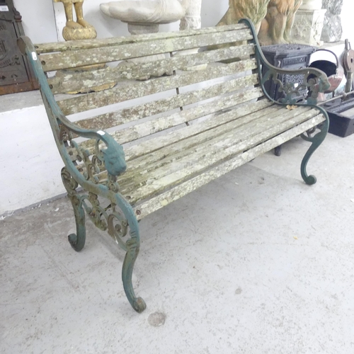 2658 - A weathered teak slatted garden bench with cast iron ends. 130x83x65cm.