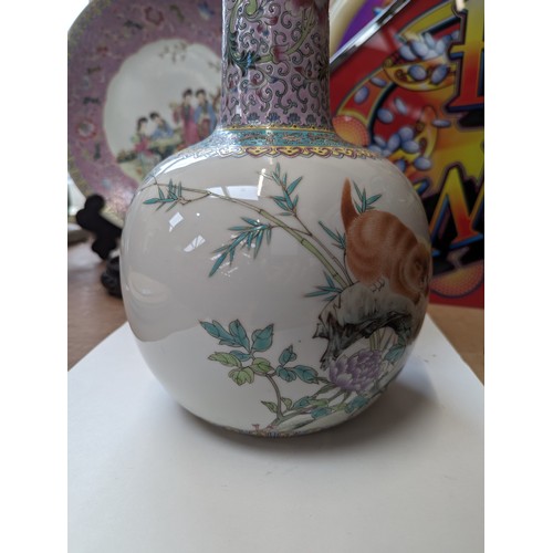 28 - A large Chinese famille rose bottle vase, enamel decoration depicting a prowling cat, on carved hard... 