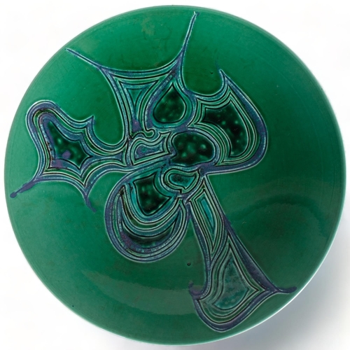 109 - Poole Pottery, a large Delphis charger with carved and glazed abstract design on green ground, maker... 