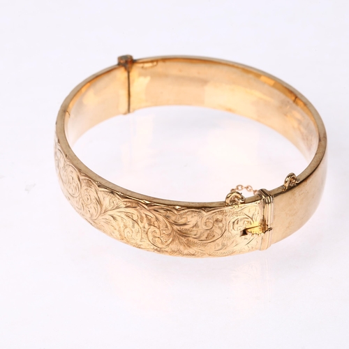 1217 - A mid-20th century 9ct gold hinged bangle, maker S&P, Birmingham 1963, with engraved foliate decorat... 