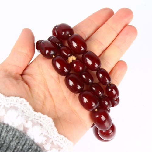 1231 - A single-strand graduated cherry amber barrel bead necklace, beads ranging from 34.4-12mm, necklace ... 