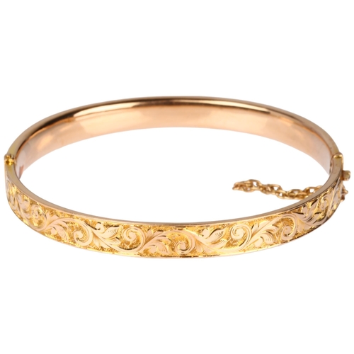 1254 - An early 20th century 15ct? rose gold hinged bangle, chased foliate decoration, band width 6.7mm, in... 