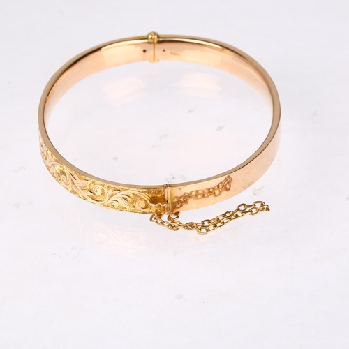 1254 - An early 20th century 15ct? rose gold hinged bangle, chased foliate decoration, band width 6.7mm, in... 