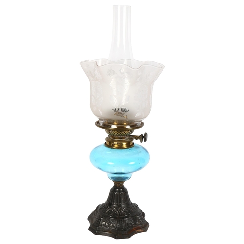 975 - A Victorian oil lamp, with etched frilled shade and blue font, on embossed cast-iron base, overall h... 