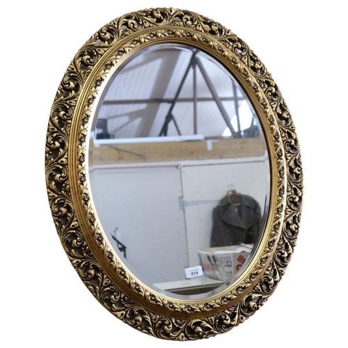 814 - A large wooden oval wall-hanging bevel-edge mirror, in ornate giltwood frame, 76cm x 63cm