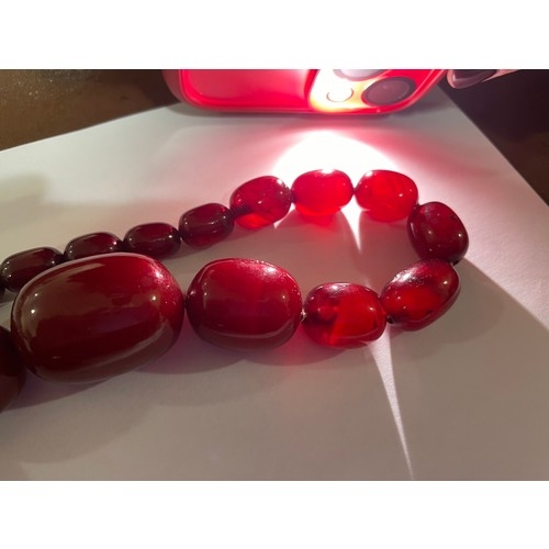 1231 - A single-strand graduated cherry amber barrel bead necklace, beads ranging from 34.4-12mm, necklace ... 