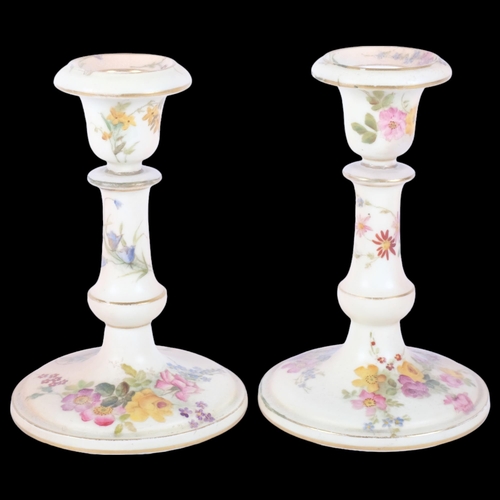 887 - A pair of Royal Worcester Blush Ivory candlesticks, with painted floral spray and gilded decoration,... 