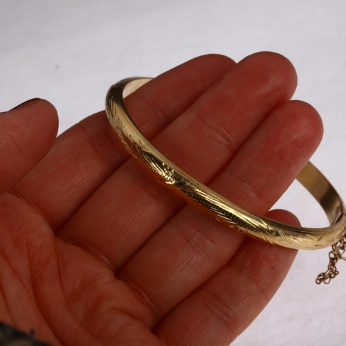 1215 - A late 20th century gold hinged bangle, indistinctly stamped 18?, allover engraved decoration, band ... 