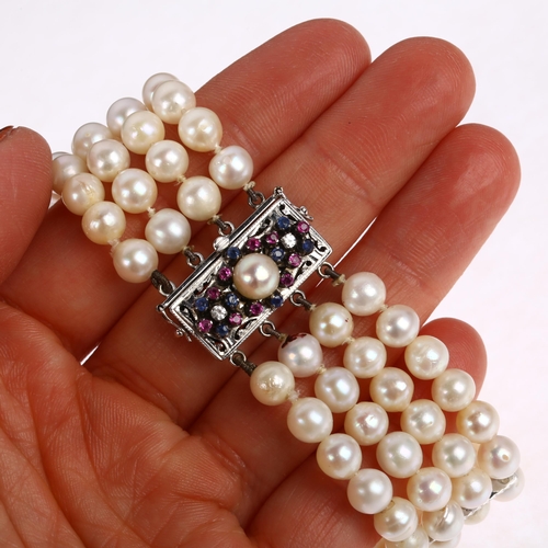 1243 - A quadruple strand pearl bead bracelet, with 18ct white gold pearl ruby sapphire and diamond clasp a... 