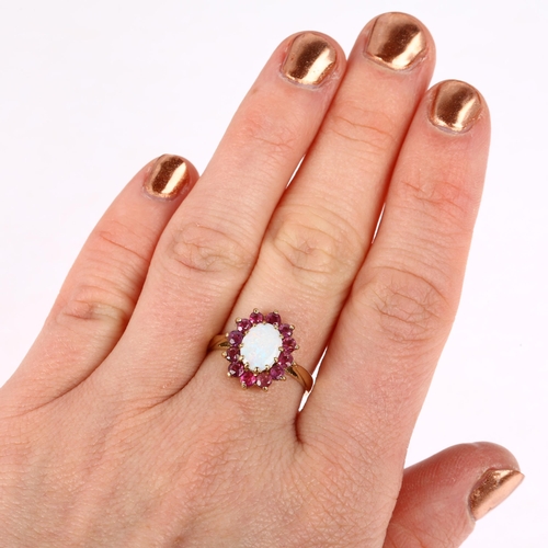 1313 - A late 20th century 9ct gold opal and ruby oval cluster ring, London 1978, claw set with oval caboch... 