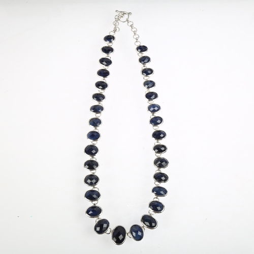 1394 - A long sterling silver graduated sapphire line necklace, rub-over set with oval rose-cut sapphires, ... 