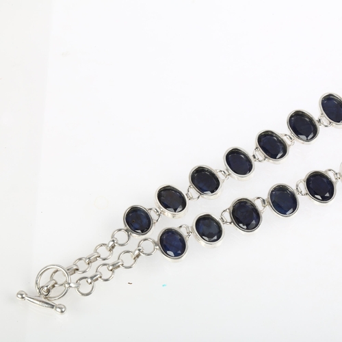 1394 - A long sterling silver graduated sapphire line necklace, rub-over set with oval rose-cut sapphires, ... 