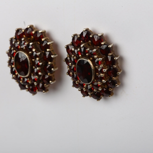 1398 - A pair of Bohemian garnet oval cluster earrings, unmarked silver-gilt settings with stud fittings, 1... 