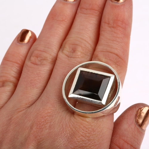 1465 - A modernist sterling silver laser-cut smoky quartz openwork ring, circular form with central rub-ove... 