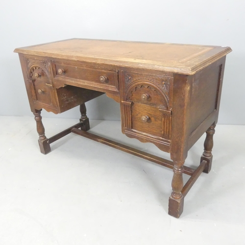 2527 - An early 20th century oak kneehole writing desk, with tooled and embossed brown leather skiver, five... 