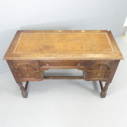 2527 - An early 20th century oak kneehole writing desk, with tooled and embossed brown leather skiver, five... 