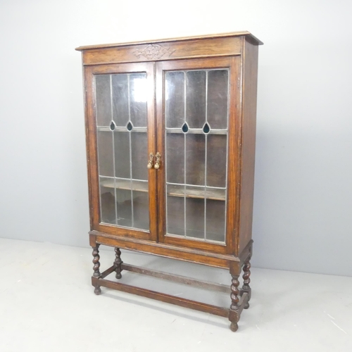 2529 - A 1930s oak bookcase, with two leadlight glazed doors, two adjustable shelves and lattice glazed sup... 