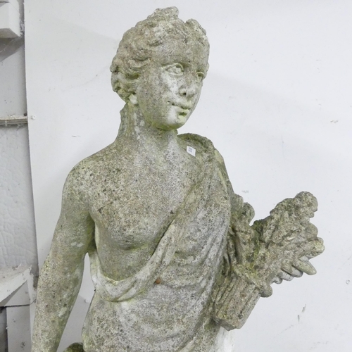 2587 - A weathered concrete garden statue, of a woman holding a wheat sheaf. Height 92cm.