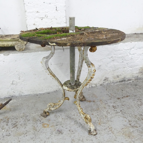 2592 - A weathered teak circular garden table on painted cast iron base. 73x79cm.