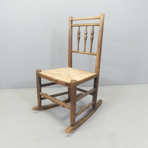 2657 - A Victorian child's oak and rush seated rocking chair, with bobbin turned back. Overall 46x83x57cm.