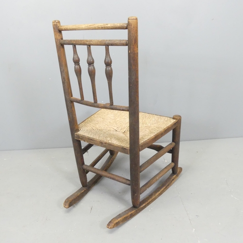 2657 - A Victorian child's oak and rush seated rocking chair, with bobbin turned back. Overall 46x83x57cm.