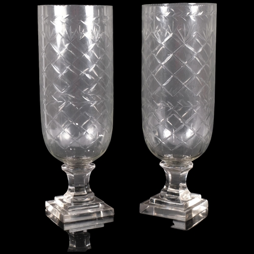 143 - A pair of cut glass hurricane lanterns on square plinths. H - 34cm.